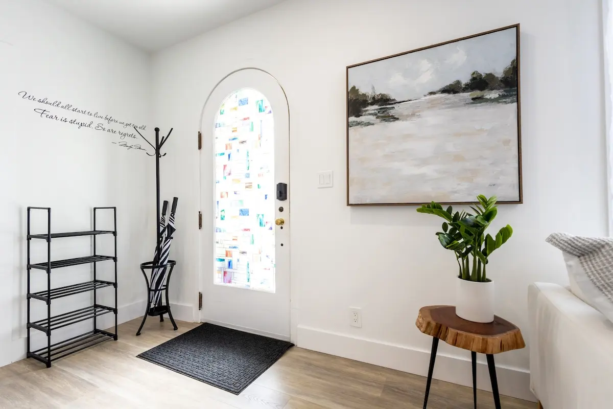 First impressions matter. Step inside to thoughtful touches like art, plants, umbrella stand, and a Marilyn quote that sets the tone: “Fear is stupid. So are regrets.”