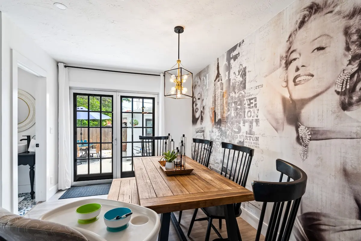 Dine under the glow of a chic chandelier and the gaze of the icon herself. This warm dining space seats 6+ and opens to the private patio.