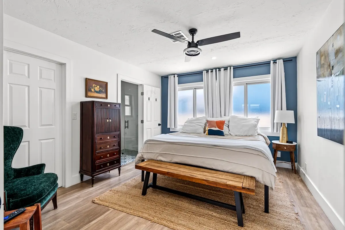 Boutique-hotel sleep: blackout curtains, a king bed dressed in plush linens, and a private bath three steps away.