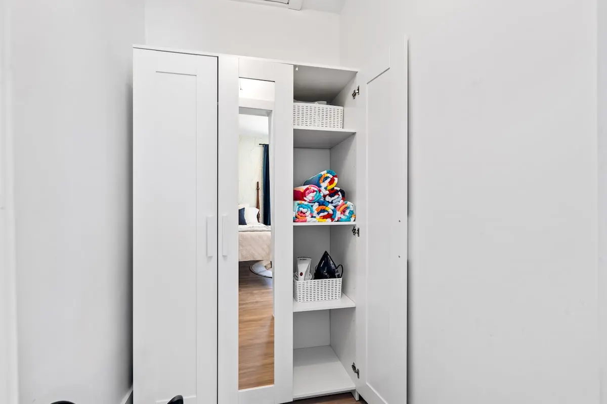 This twin bedroom includes its own storage cabinet stocked with beach towels, an iron and steamer, and extra essentials — everything you need for a smooth, sunny stay.